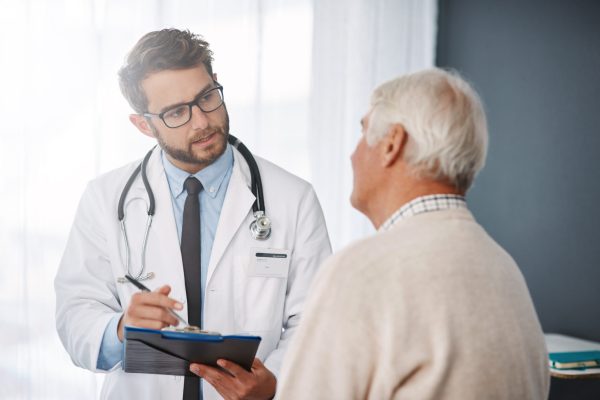 Cropped shot of a young male doctor going through medical records with his senior male patient.